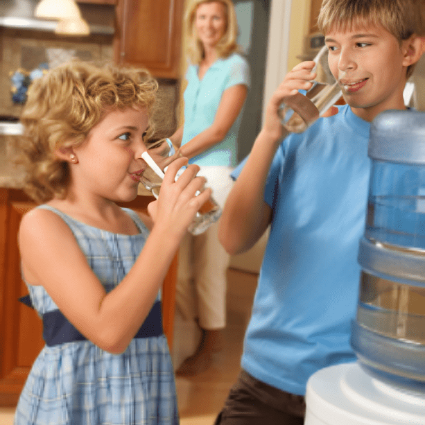 A boy and girl drinking water from a bottle.